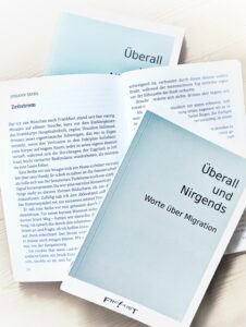 Sammelband „Überall und Nirgends – Worte über Migration“ mit aufgeschlagenen Seiten des Beitrags „Zeitstrom“ von Johann Seidl.